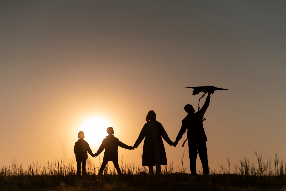 Famille se tenant la main au coucher du soleil, représentant l'unité familiale.