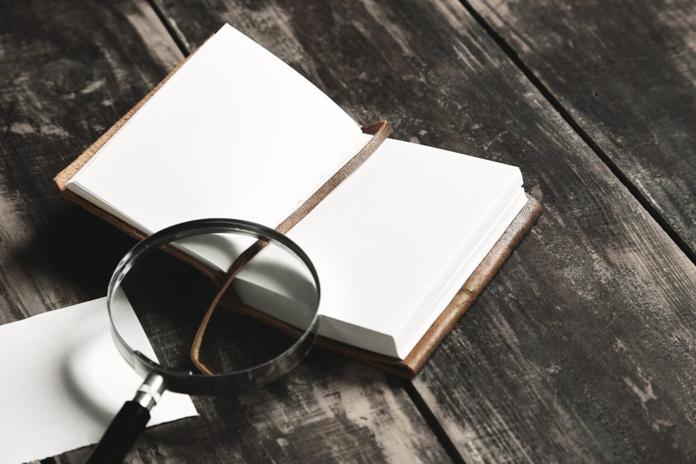 Carnet ouvert avec une loupe sur une table en bois, symbolisant la collecte d'indices.